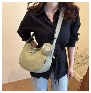 Light green crescent nylon crossbody bag with matching round coin purse shown on model