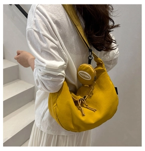 Detail of yellow nylon crescent tote bag with detachable round mini coin purse and strap