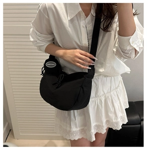 Detail of a black nylon half-moon crossbody bag with a round coin purse on the strap