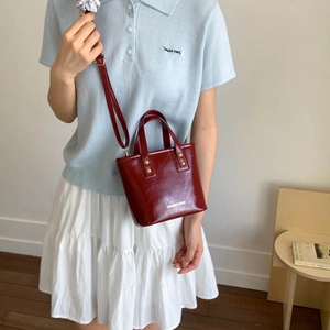 Elegant wine red bucket bag with gold lettering shown on model for a stylish look