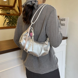 Silver crescent dumpling bag with knotted strap and heart charm worn by a model