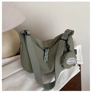 Detail of army green nylon crescent bag with wide strap and round coin purse attachment