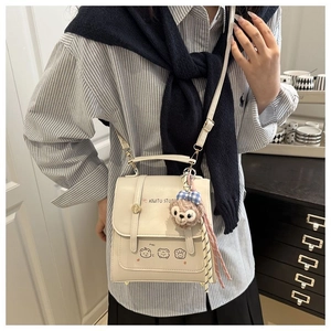Detail of cream PU leather backpack featuring cute cartoon bear prints and plush pendant