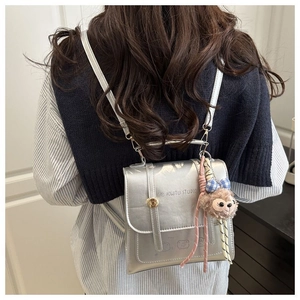 Detail view of silver metallic PU mini backpack with brand logo and soft plush charm