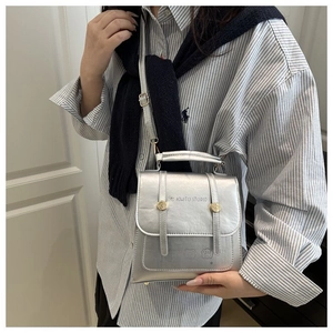 Detail of silver leather crossbody bag with metallic finish and gold rivet accents