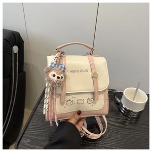 Close-up of pink and white backpack featuring a cute bear print and plush charm