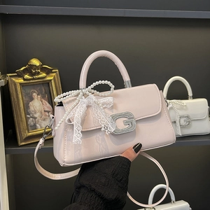 Detail of pink faux leather bag with lace trim, pearl bow, and sparkling G buckle