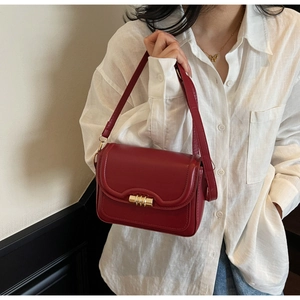 Close-up of vintage dark red leather square bag with gold spiral lock and fine stitching