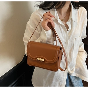 Detail of caramel leather square crossbody bag with gold cylindrical lock and adjustable strap