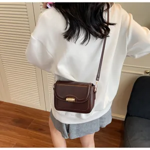 Detail view of the chocolate brown PU leather crossbody bag with golden metal clasp