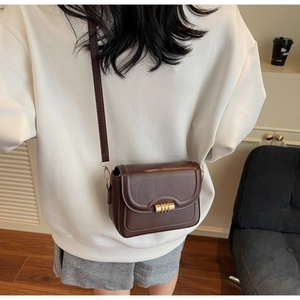 Detailed view of deep brown vintage leather crossbody bag with golden cylinder lock