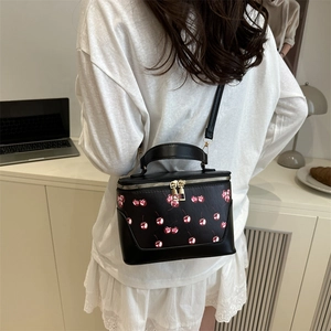 Retro black cherry print bucket bag with gold hardware shown in a modern home setting