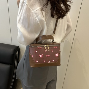 Retro brown bucket bag with cherry print pattern shown on model for daily style