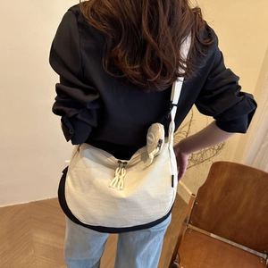 Minimalist beige half-moon canvas crossbody bag with round coin pouch and woven zipper pull