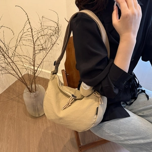 Khaki hobo canvas shoulder bag with wide strap styled by a model in a natural setting