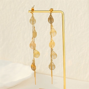 Long gold tassel earrings featuring hollow leaf pendants on a metal display stand