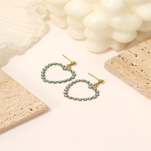 Orecchini vintage a cuore in oro con perle blu su sfondo decorativo in pietra