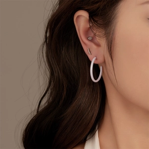 Close-up of a white resin hoop earring with marquise crystal cartilage studs on a model