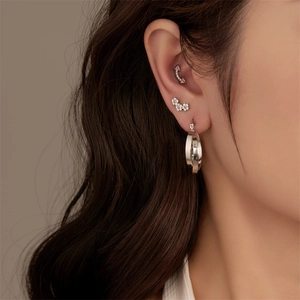 Close-up of silver G23 titanium stud earrings and ear cuffs with sparkling zircon stones