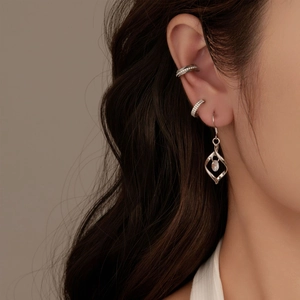 Macro-opname van zilveren geometrische oorbellen en ear cuffs gedragen op model