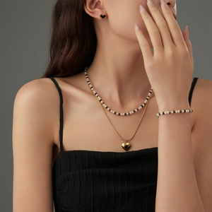 Modisches Titanschmuck-Set mit Herzanhängern und schwarzen Perlenketten an einem Model