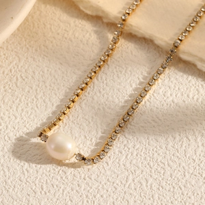 Elegant gold choker necklace with a large white pearl pendant and shimmering pavé crystals