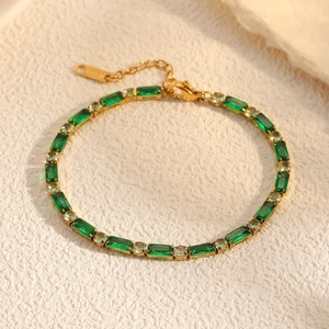 Elegant gold-plated tennis bracelet featuring emerald green zircon stones on marble stone background