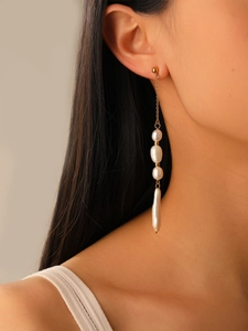 Detailed shot of long drop earrings with baroque pearls and delicate gold chains