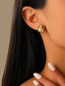 Close-up of luxury gold floral stud earrings with pearl center on model