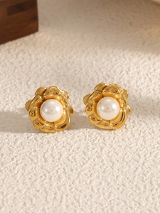 Detailed macro shot of vintage gold camellia earrings featuring a white pearl center