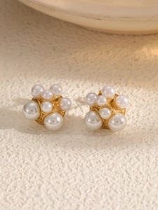 Detail of vintage cluster pearl earrings with gold-plated base on beige stone background
