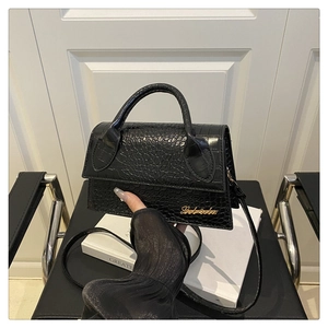 Detail of black crocodile embossed leather mini bag with gold logo and top handle