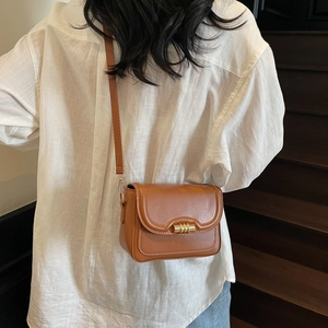 Vintage brown leather crossbody square bag with gold lock shown on model outfit