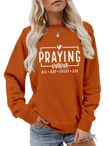 Détail du sweat orange citrouille avec inscription Praying Mama blanche sur le torse