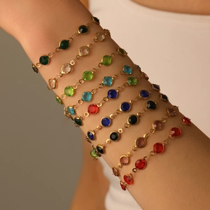 Eleganti bracciali dorati con cristalli sfaccettati colorati sul polso di una donna