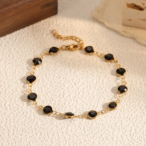 Dettaglio del bracciale a catena dorata regolabile con dodici pietre tonde nere sfaccettate