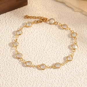 Dettaglio di bracciale a catena dorata con cristalli rotondi e chiusura a moschettone