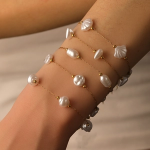 Bracelet de perles baroques avec breloques coquillage plaqué or 18k porté au poignet