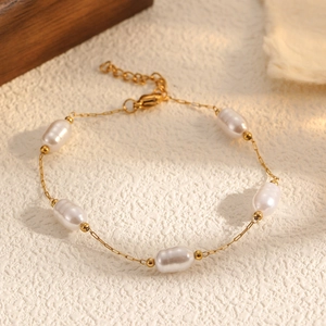 Gros plan sur le bracelet perle en or avec perles ovales blanches et fermoir mousqueton