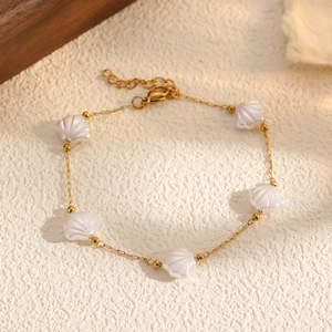 Détail du bracelet en acier titane doré avec breloques coquillage blanc et fermoir mousqueton