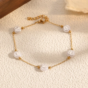 Détail d'un bracelet en acier doré orné de cinq perles blanches rondes et élégantes