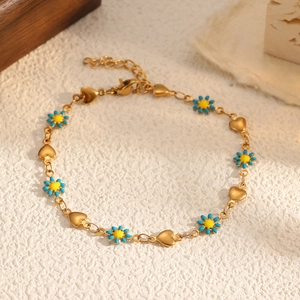 Bracelet marguerite doré élégant avec breloques en cœur et tournesols jaunes sur fond texturé