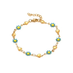 Détail du bracelet chaîne dorée avec marguerites en émail bleu et breloques en cœur