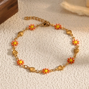 Détail du bracelet marguerite doré avec pétales en émail orange et breloques en cœur