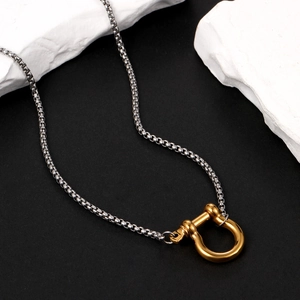 Polished silver square chain with a golden horseshoe pendant on black and white stone