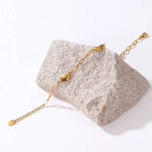 Elegant gold heart paperclip chain bracelet in stainless steel on a natural stone base