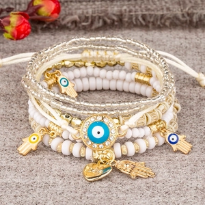 Detail of layered beaded bracelets with Evil Eye and Hamsa Hand charms and Love heart