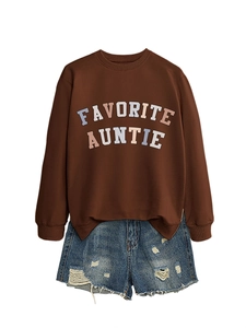 Dettaglio della scritta Favorite Auntie su felpa marrone e pantaloncini di denim