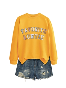 Dettaglio della felpa gialla Favorite Auntie abbinata a shorts in denim strappati