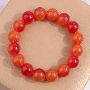Elegant natural red agate beaded bracelet for women on a rustic wooden display base